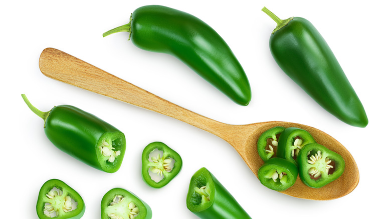 Whole and cut up jalapenos with wooden spoon