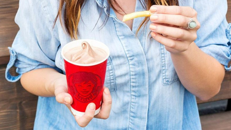 woman dipping fry into Wendy's Frosty