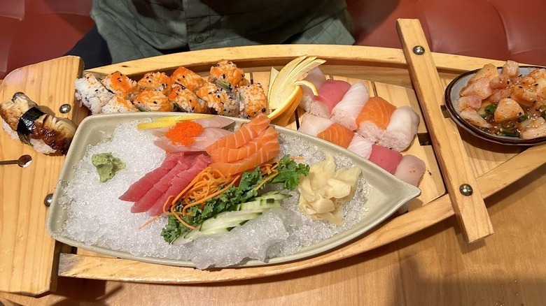 Sushi boat with sashimi, sushi roll, and vegetables