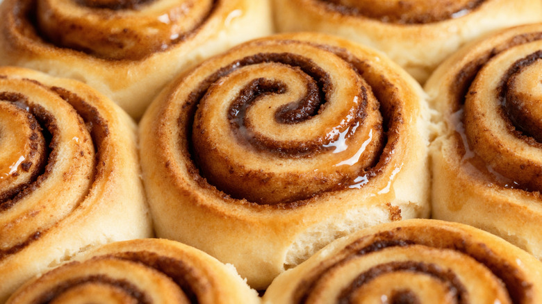 A close-up shot of packed-together cinnamon rolls covered in a thin layer of sheer glaze.