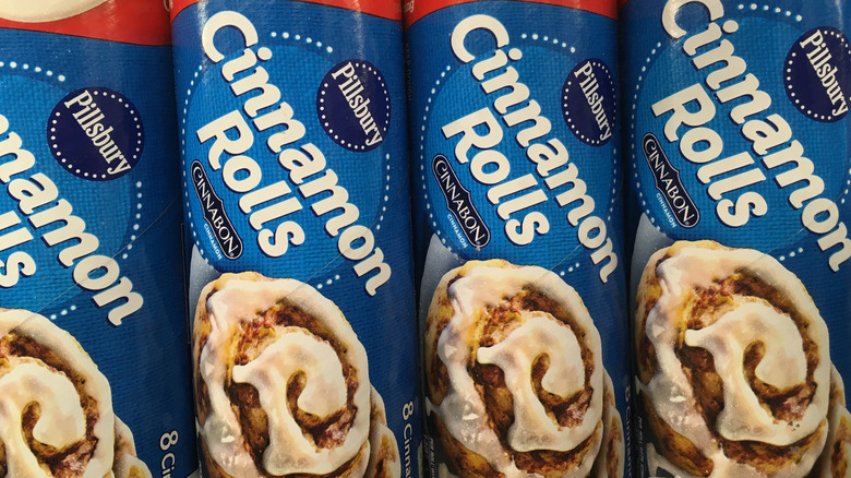 Four cans of Pillsbury cinnamon rolls lined up next to each other