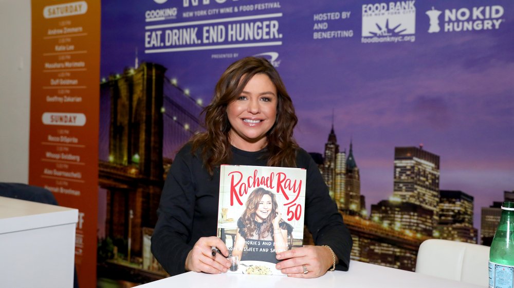 Rachael Ray holding up her cookbook