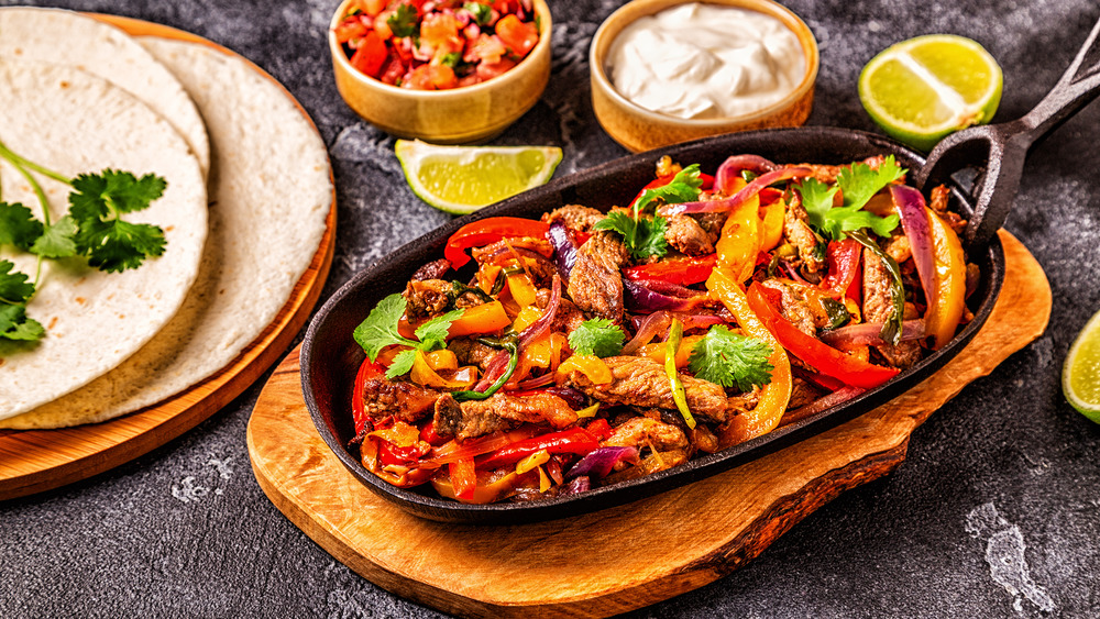 a platter of steak fajitas with garnishes