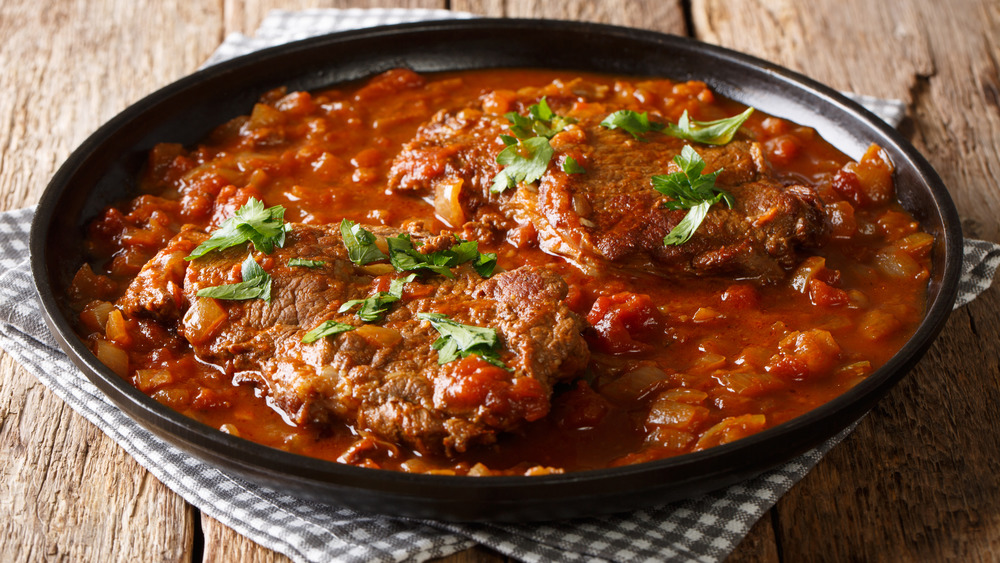 Swiss steak, smothered steak, cubed steak in a skillet with tomato gravy, tomato sauce