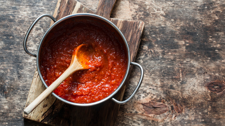 Tomato sauce in a sauce pan with a wood spoon