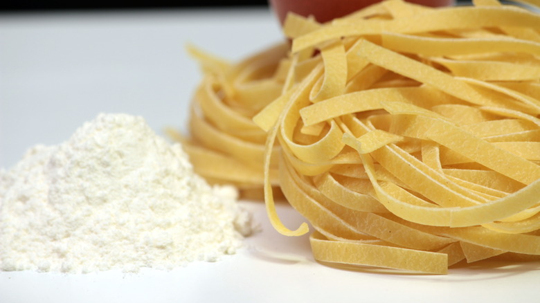 Ground white flour next to pasta noodles