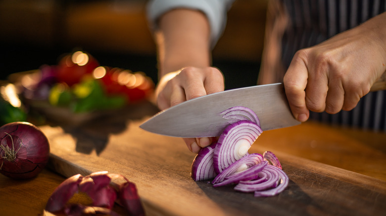 Person slicing red onions