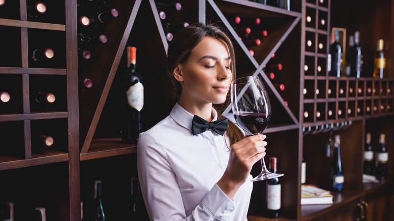 Female wine steward smelling a glass of red wine