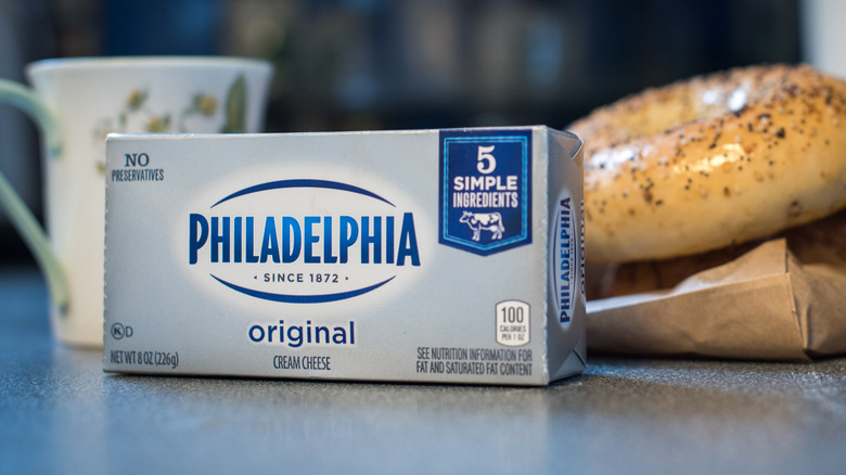 A block of Philadelphia cream cheese next to bagel