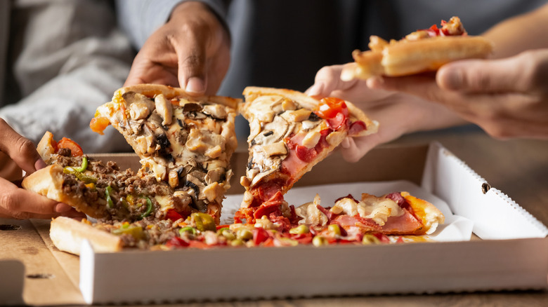 Hands pulling pizza out of a white box