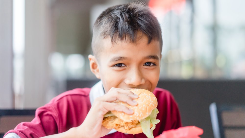 Teenager eating chicken sandwich