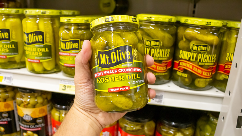 person holding jar of mt. olive pickles in grocery store