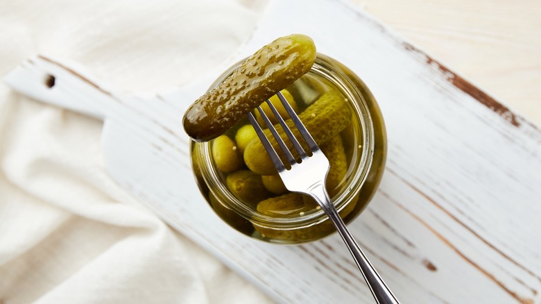 fork spearing pickle over open jar