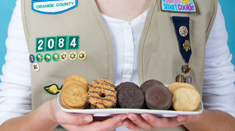 A Girl Scout holding a plate of a variety of cookies