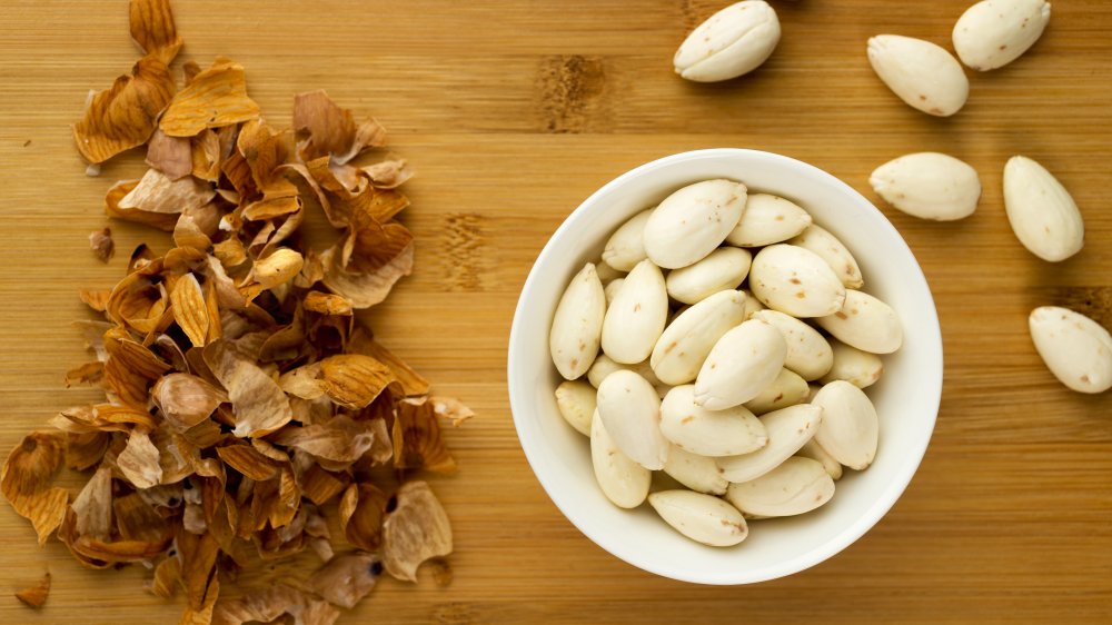 bowl of blanched almonds with almond skins on side