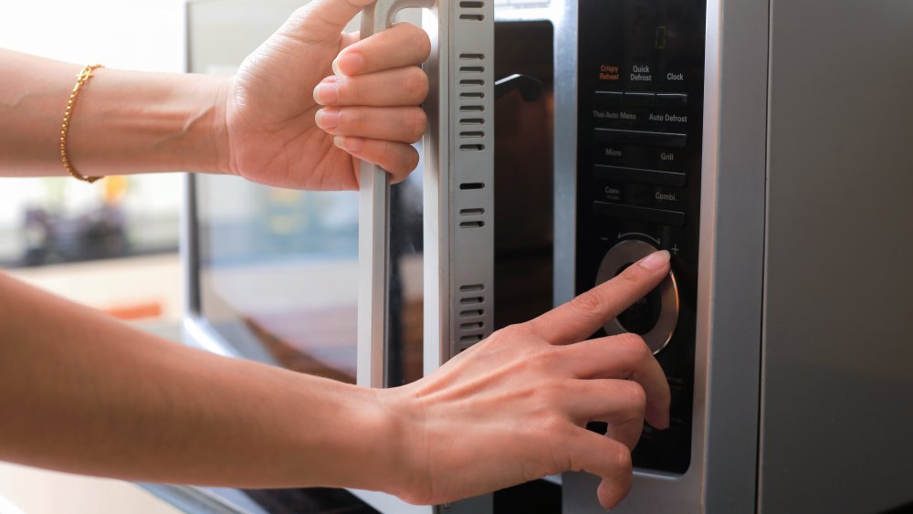 woman adjusting settings on microwave