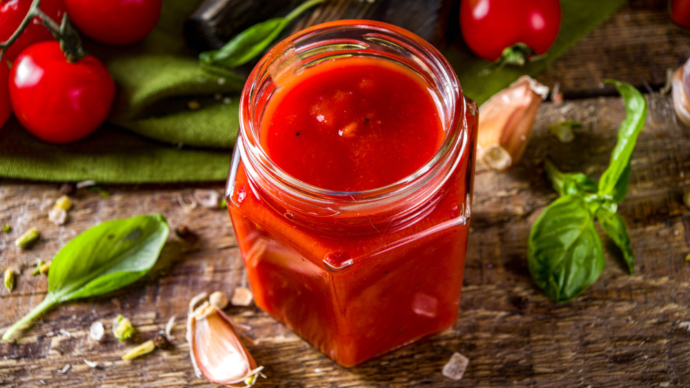 A jar or marinara sauce with basil, garlic, and tomatoes