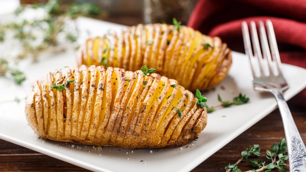 Hasselback potatoes on white plate with fork
