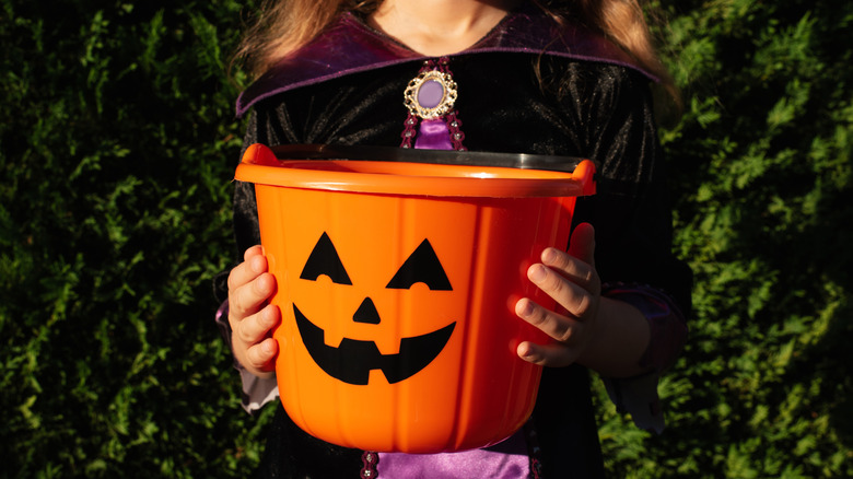 Girl dressed in Halloween costume holding a trick-or-treat bucket