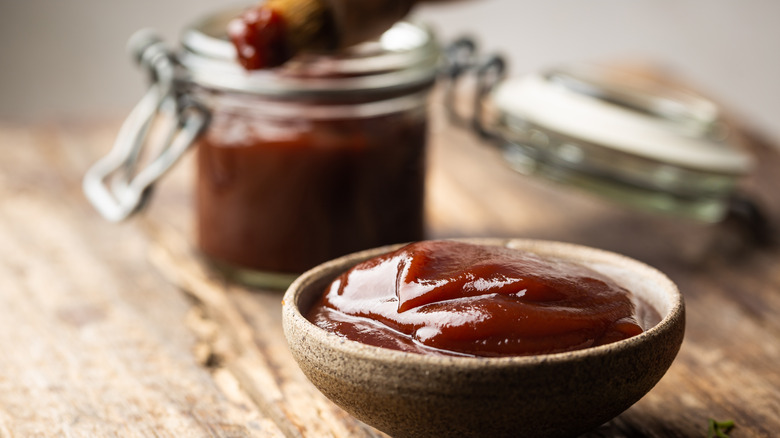 small bowl of barbecue sauce with jar in the background