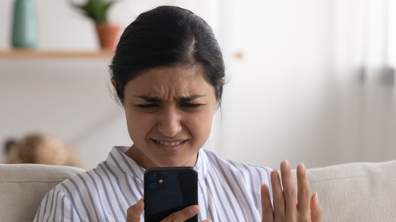 Woman looks angrily at phone