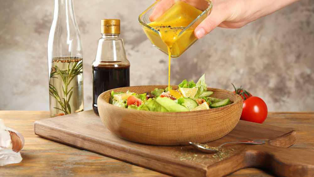 Woman pouring salad dressing