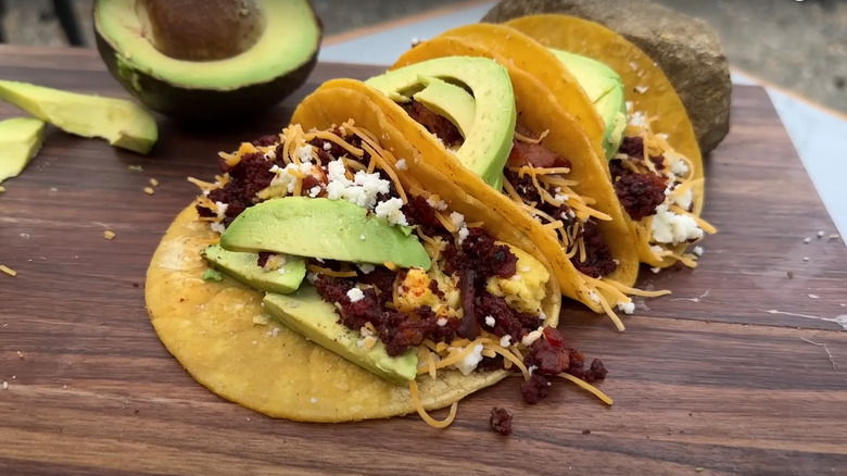 Breakfast tacos with bacon and chorizo topped with cheese and avocados by Cowboy Kent Rollins