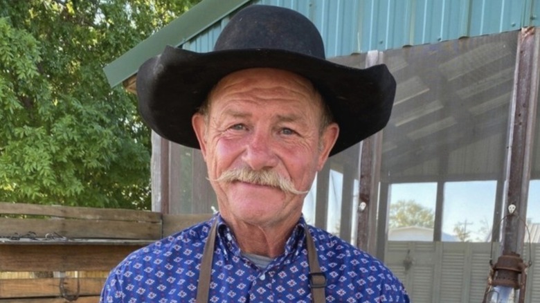 Cowboy Kent Rollins outside with a cowboy hat and apron on