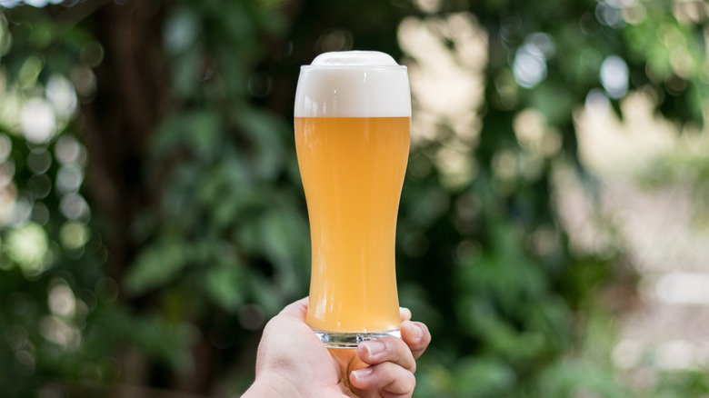 hand holding glass of sudsy beer
