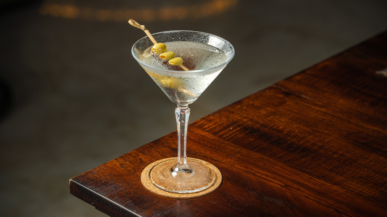 martini with olives on wooden table