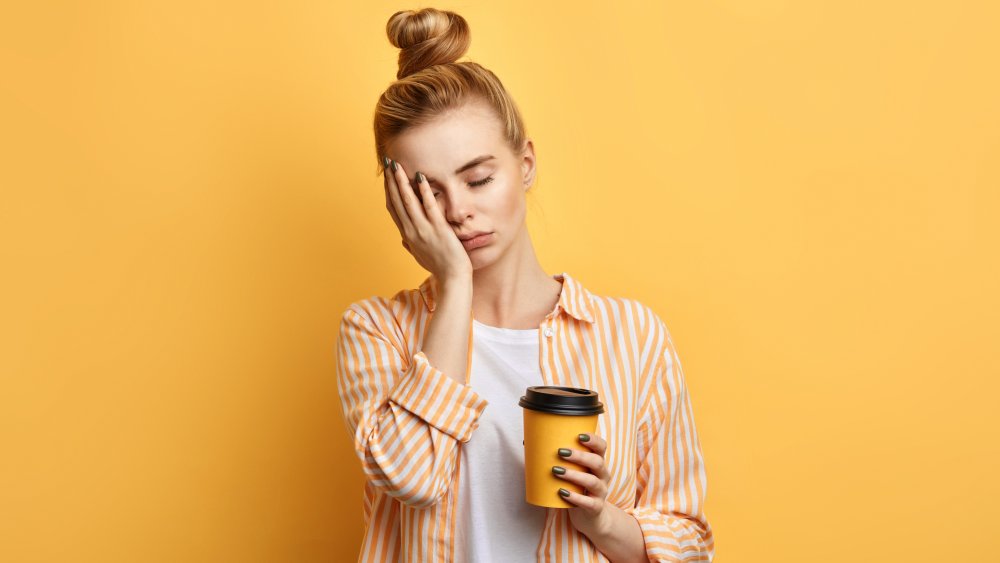 Tired woman holding cup of coffee