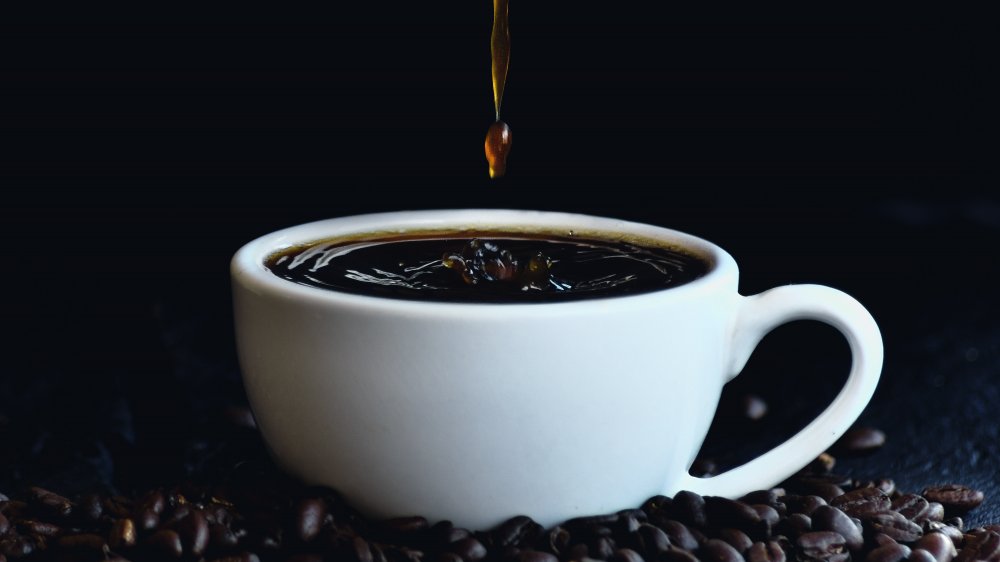 Cup of coffee pouring with coffee beans