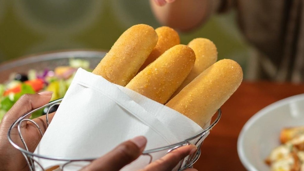 Hands holding basket of Olive Garden breadsticks