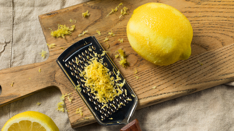 Lemon zest, grater, and lemon on cutting board