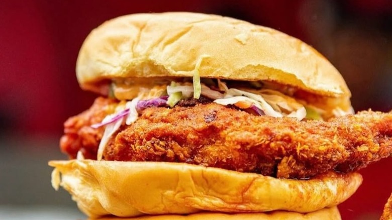 A close-up of a fried chicken sandwich with coleslaw and sauce