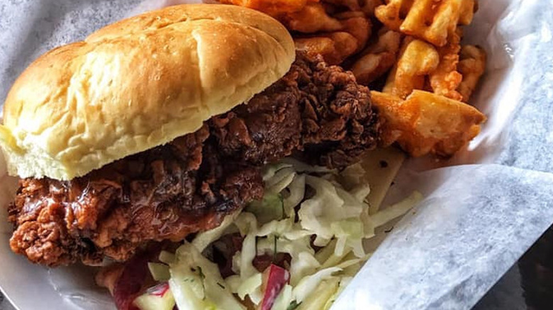A fried chicken sandwich served with waffle fries and coleslaw in a basket