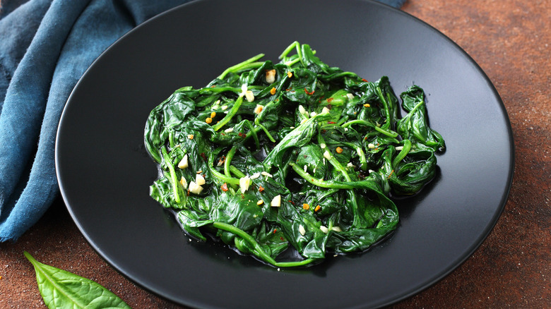 Cooked spinach on black plate