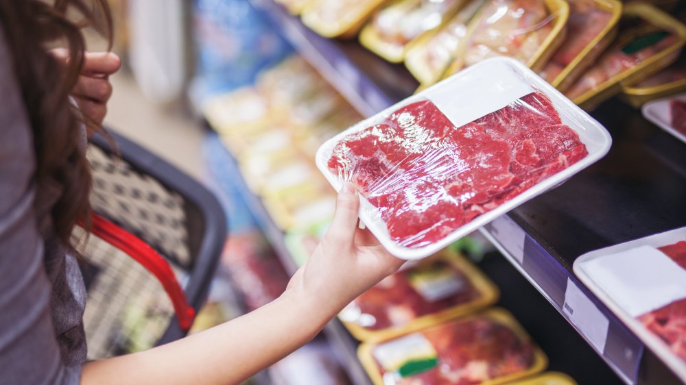 Woman holding beef package at grocer