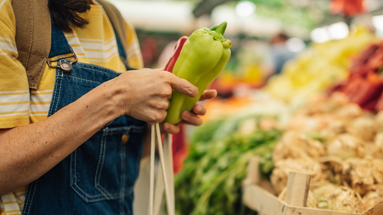 Person holding pepper at vegetable stand
