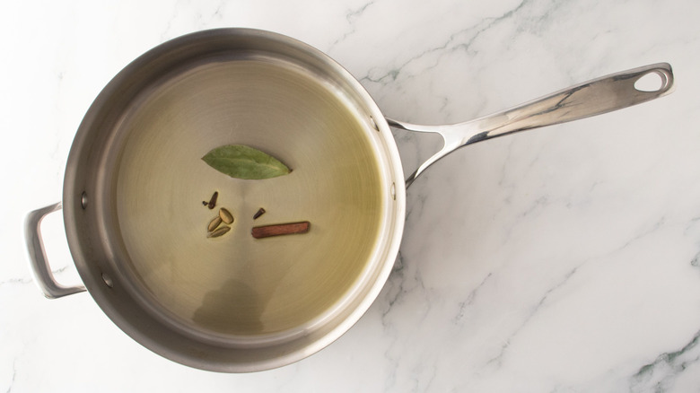 Oil, spices, and bay leaf in pan
