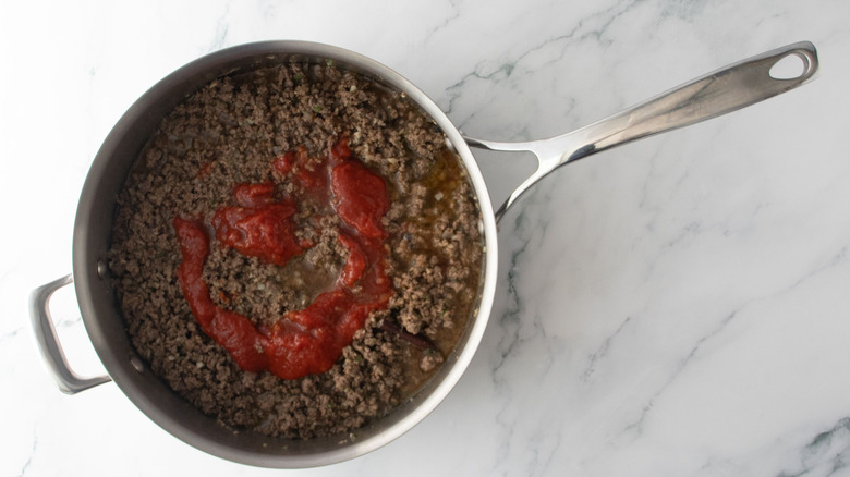 Cooked ground beef with tomato puree in pan