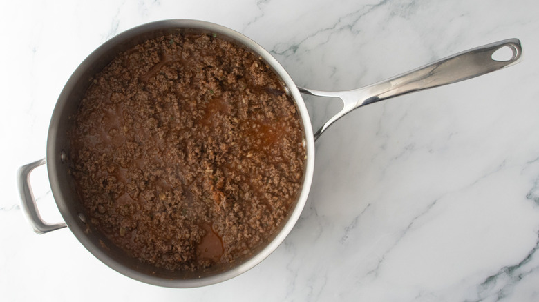 Cooked ground beef and liquid in pan