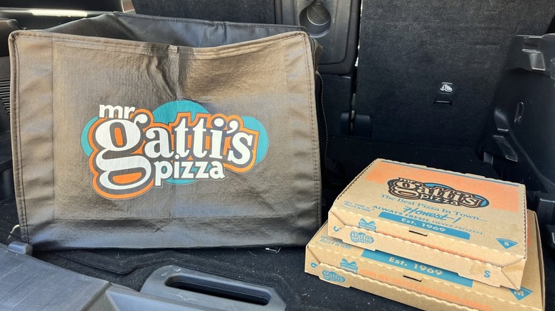 Pizza boxes and delivery bag from Mr. Gatti's Pizza in car trunk.
