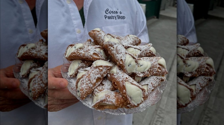 Owner of Circo's Pastry Shop holding tray of cannoli.