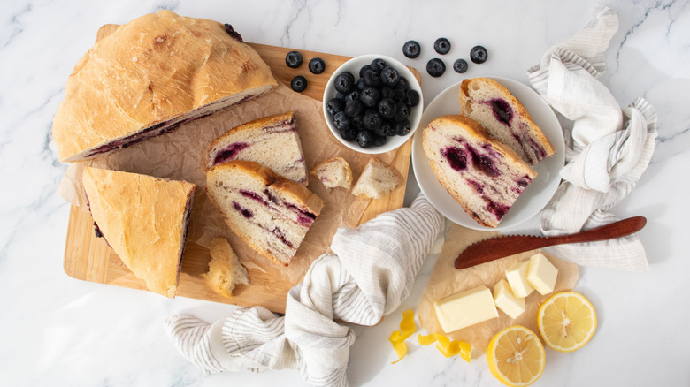 Lemon blueberry bread slices surrounded by blueberries, butter, and lemons
