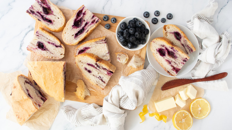Lemon blueberry bread slices surrounded by blueberries, butter, and lemons