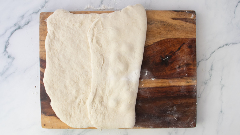 Dough rectangle with one half folded over middle on wooden board