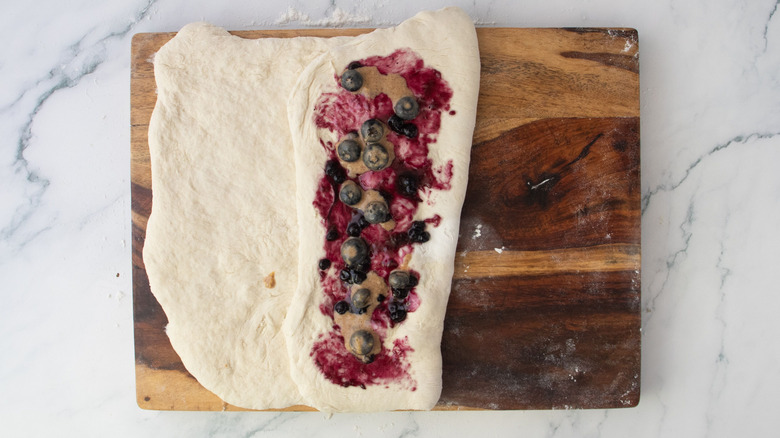 Dough half folded over on itself topped with blueberry jam and spiced blueberries