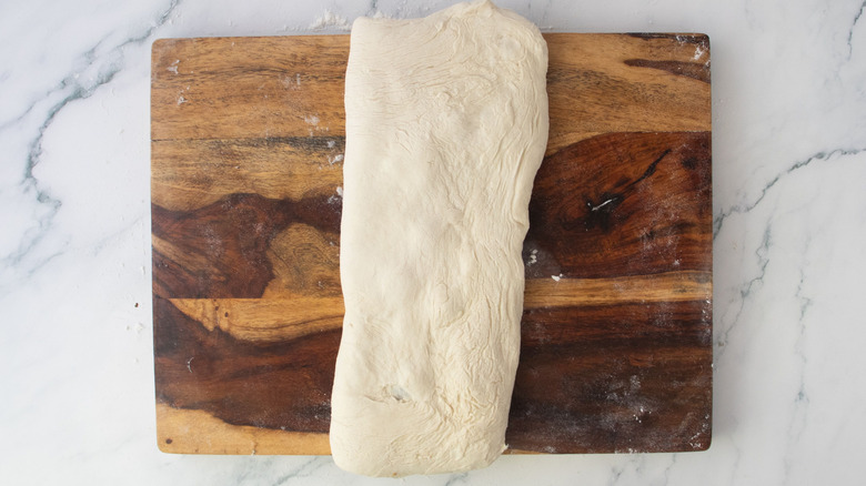 Long and thin dough rectangle on wooden board