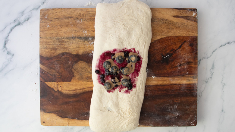Long dough rectangle topped in the middle with jam and spiced blueberries